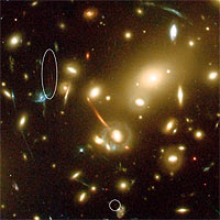 This close-up of the large galaxy cluster Abell 2218 shows how this cluster acts as one of nature’s most powerful ‘gravitational telescopes’ and amplifies and stretches all galaxies lying behind the cluster core (seen as red, orange and blue arcs). Such natural gravitational ‘telescopes’ allow astronomers to see extremely distant and faint objects that could otherwise not be seen. 
<P>
A new galaxy (split into two ‘images’ marked with an ellipse and a circle) was detected in this image taken with the Advanced Camera for Surveys on board the NASA/ESA Hubble Space Telescope. The extremely faint galaxy is so far away that its visible light has been stretched into infrared wavelengths, making the observations particularly difficult. 
<P>
The galaxy may have set a new record in being the most distant known galaxy in the Universe. Located an estimated 13 billion light-years away (z~7), the object is being viewed at a time only 750 million years after the big bang, when the Universe was barely 5 percent of its current age. 
<P>
In the image the distant galaxy appears as multiple ‘images’, an arc (left) and a dot (right), as its light is forced along different paths through the cluster’s complex clumps of mass (the yellow galaxies) where the magnification is quite large. 
<P>
The colour of the different lensed galaxies in the image is a function of their distances and galaxy types. The orange arc is for instance an elliptical galaxy at moderate redshift (z=0.7) and the blue arcs are star forming galaxies at intermediate redshift (z between 1 and 2.5). 
<P>
Credits: European Space Agency, NASA, J.-P. Kneib (Observatoire Midi-Pyrénées) and R. Ellis (Caltech)