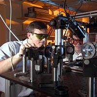 Georgia Tech Physicists Alex Kuzmich (left) and Dzmitry Matsukevich operate optical equipment used to transfer information from two different groups of atoms onto a single photon. 
Georgia Tech Photo: Gary Meek 
