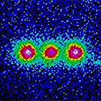 This colorized image shows the fluorescence from three trapped beryllium ions illuminated with an ultraviolet laser beam. Black and blue areas indicate lower intensity; red and white indicate higher intensity. <BR><BR>Credit: NIST