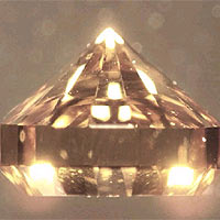 This photograph shows a synthetic brilliant cut single-crystal diamond grown by chemical vapor deposition, CVD. About 2.5 mm high, this crystal was grown in about 1 day at Carnegie. The very bottom (table) of the crystal is a type 1b seed: hence the yellow tint which is due to internal reflection (the CVD diamond is transparent). [C.S. Yan et al., Physica Status Solidi (a) 201,R25 (2004)(PDF 288KB)]. The researchers have also reported that these CVD diamonds are capable of easily generating ultrahigh pressures to at least 200 GPa.[W.L. Mao et al., Appl. Phys. Lett. 83, 5190 (2003)(PDF 288KB)].
Image copyright: Physica Status Solidi.