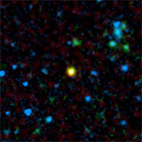 This false-color image from NASA's Spitzer Space Telescope shows a distant galaxy (yellow) that houses a quasar, a super-massive black hole circled by a ring, or torus, of gas and dust.<br/>
<br/>
Credit: NASA