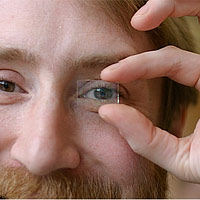 <p>
	Richard Lunt, one of the researchers who developed the new transparent solar cell, demonstrates its transparency using a prototype cell.</p>
<p>
	Photo: Geoffrey Supran</p>
